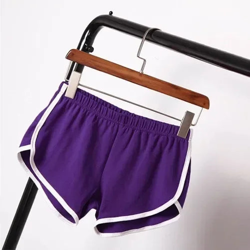 Purple shorts with white trim hanging on a wooden hanger against a white background